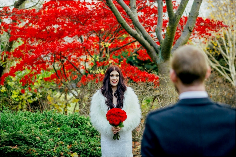 bride-looking-towards-husband-red-tree-background