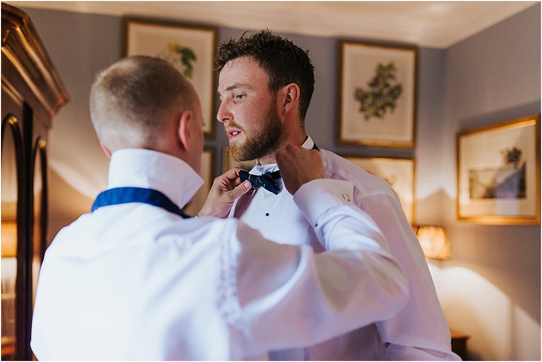 groomsman-tying-grooms-tartan-bow-tie