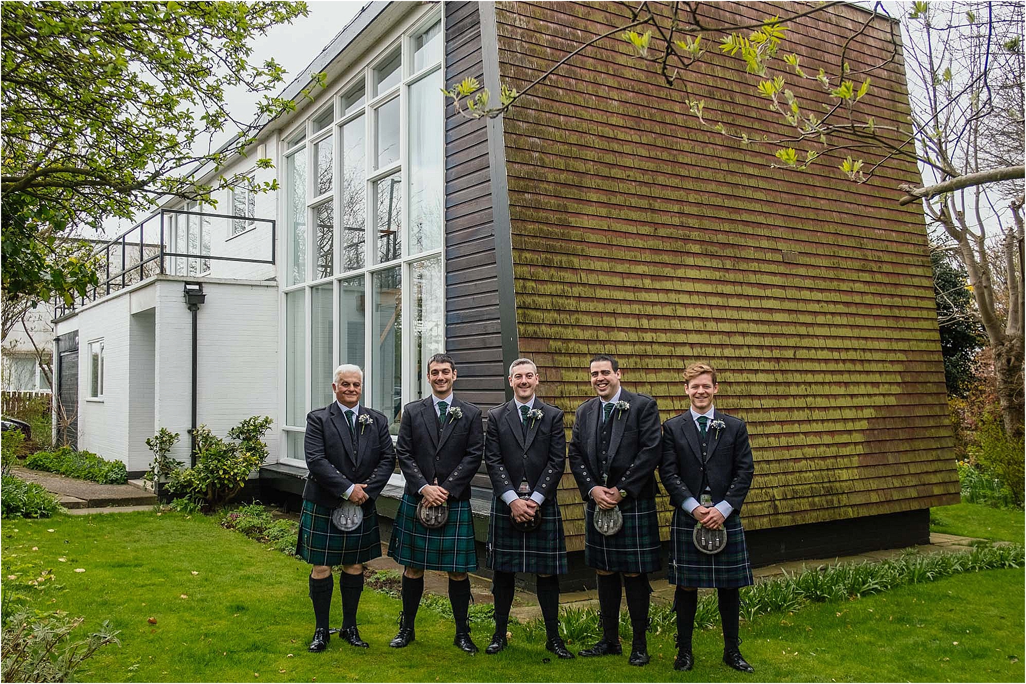 groom-groomsmen-standing-outside-house