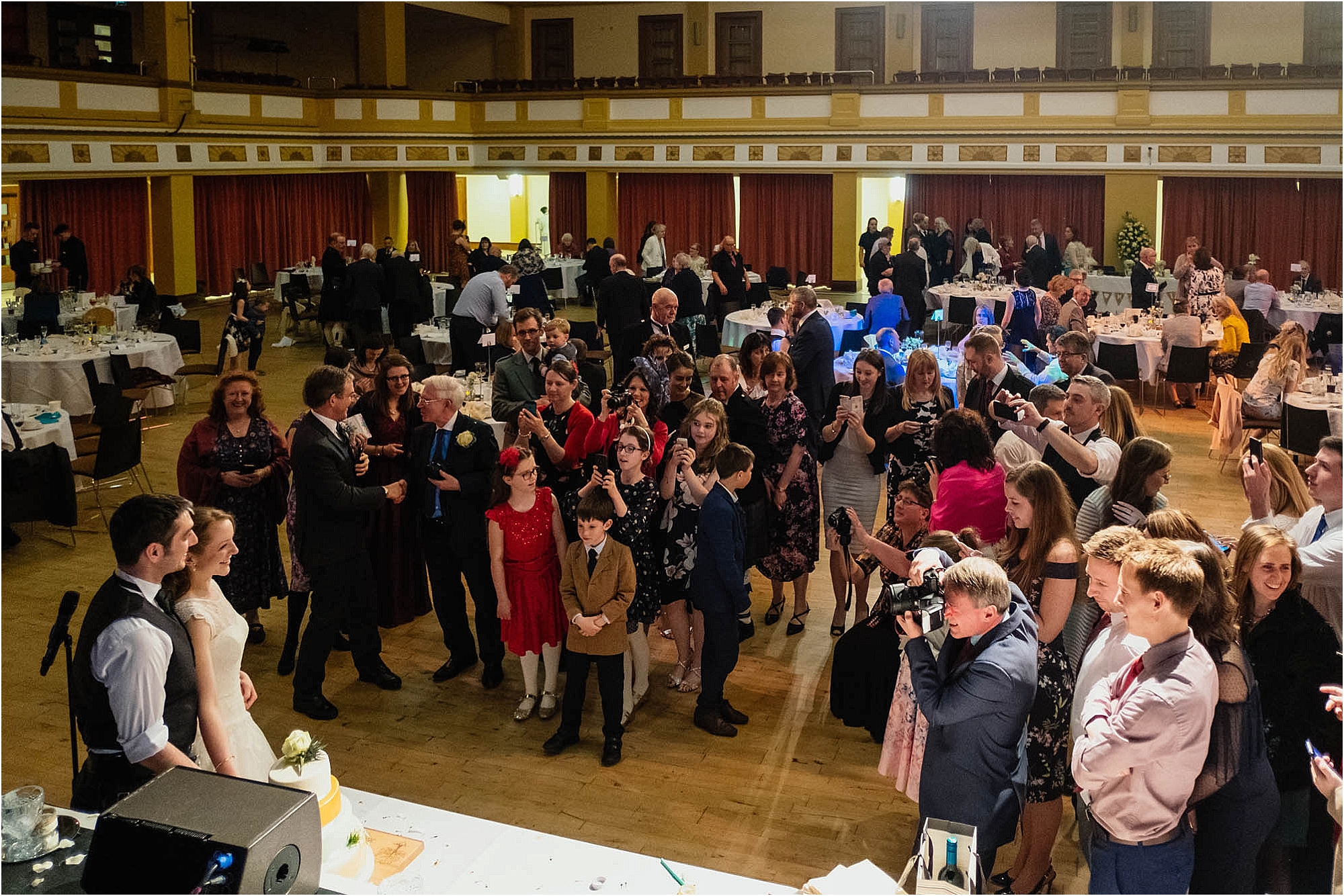 wedding-guests-watching-bride-groom-cutting-cake