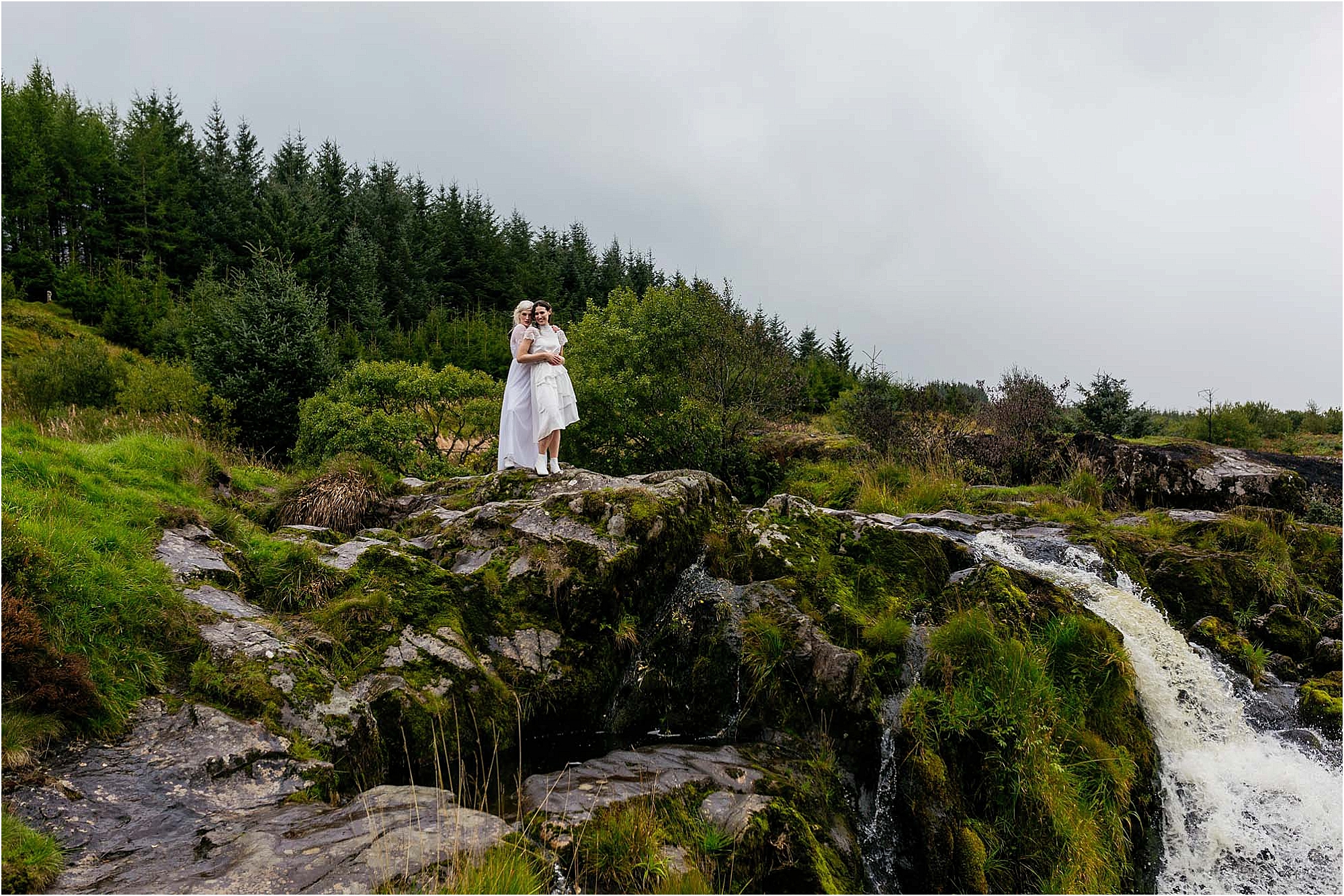 same-sex-couple-standing-at-top-of-waterfall