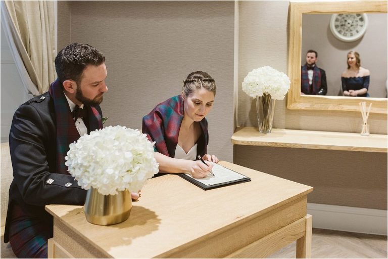 bride-and-groom-sign-the-register-while best-man-and-bridesmaid-watch