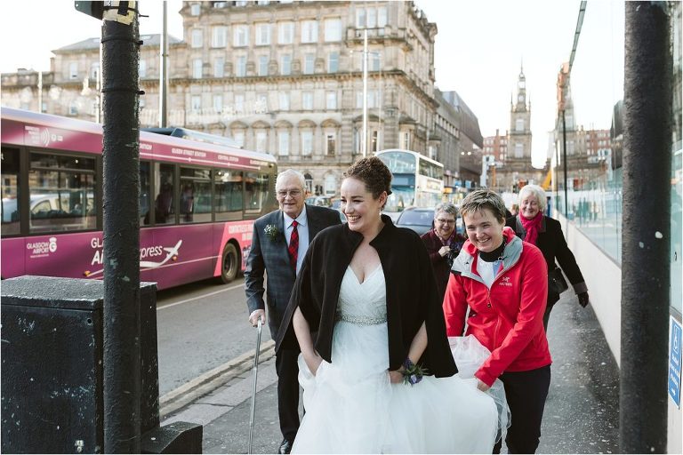friend-helps-bride-with-dress-as-they-walk-to-ceremony