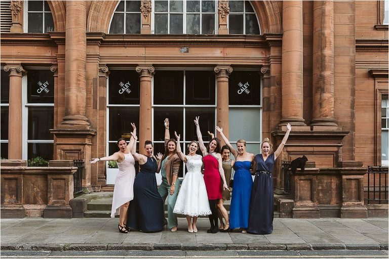 bride-poses-with-friends-outside-venue-and-cheering