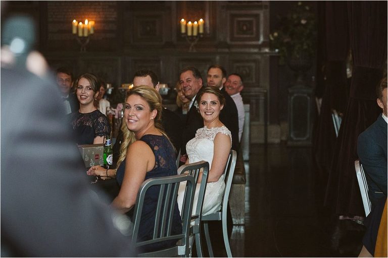 bride-smiles-at-groom-while-he-speaks-about-her