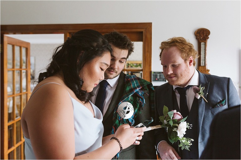 groom-best-man-and-bridesmaid-looking-at-phone-working-out-how-ceremony-playlist