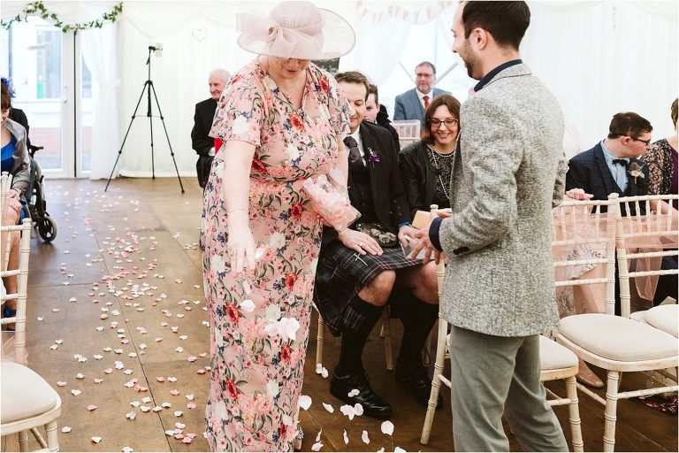 grooms-mum-scattering-faux-rose-petals-on-floor