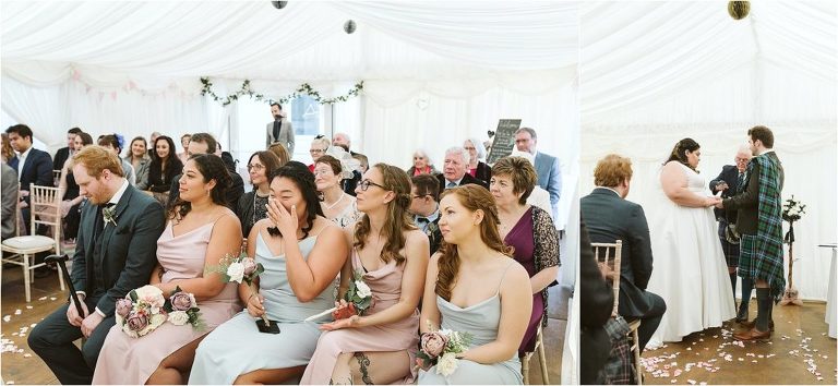 guests-smiling-whiles-bride-and-groom-exchange-rings