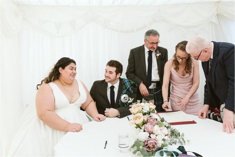 bride-and-groom-sign-register-with-witnesses