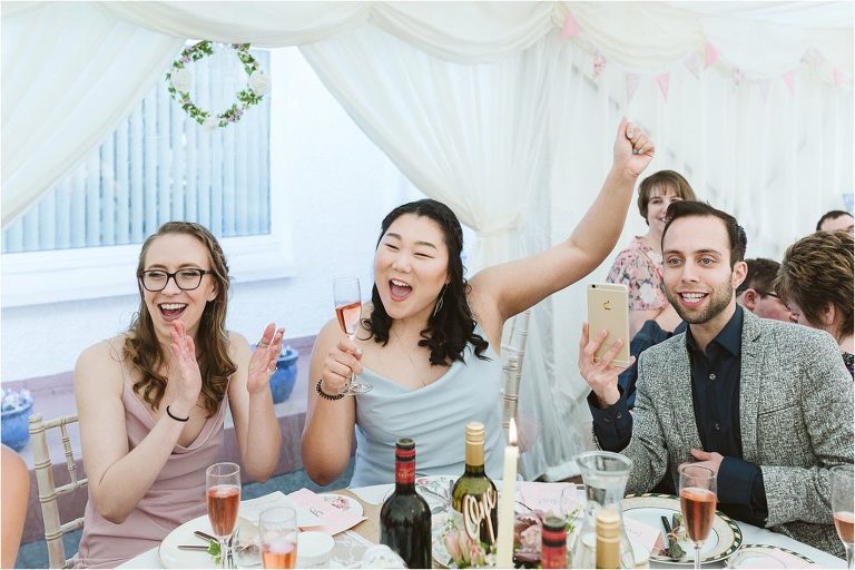 guests-cheering-while-bride-and-groom-cut-cake