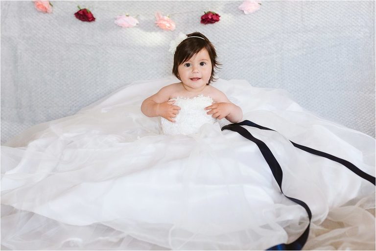 one-year-old-girl-sitting-in-mums-wedding-dress