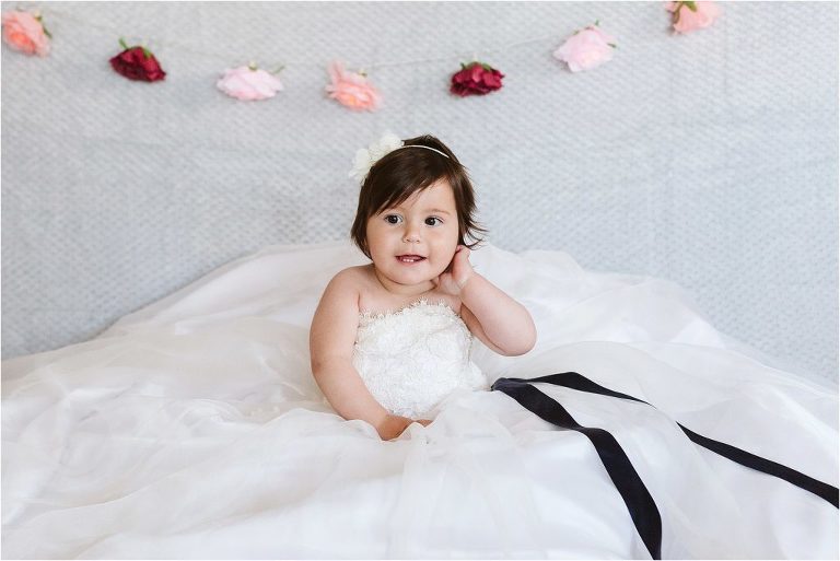 one-year-old-girl-sitting-in-mums-wedding-dress