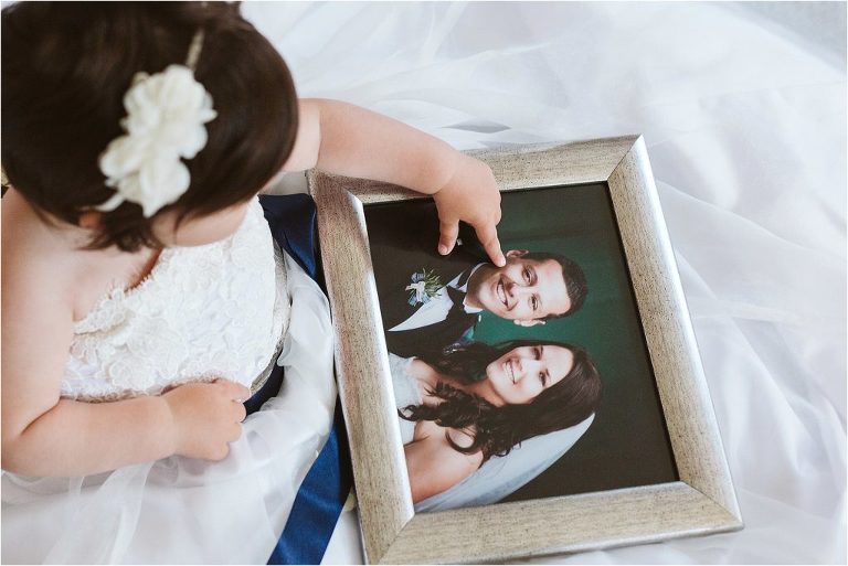 little-girl-points-at-picture-of-parents-on-their-wedding-day