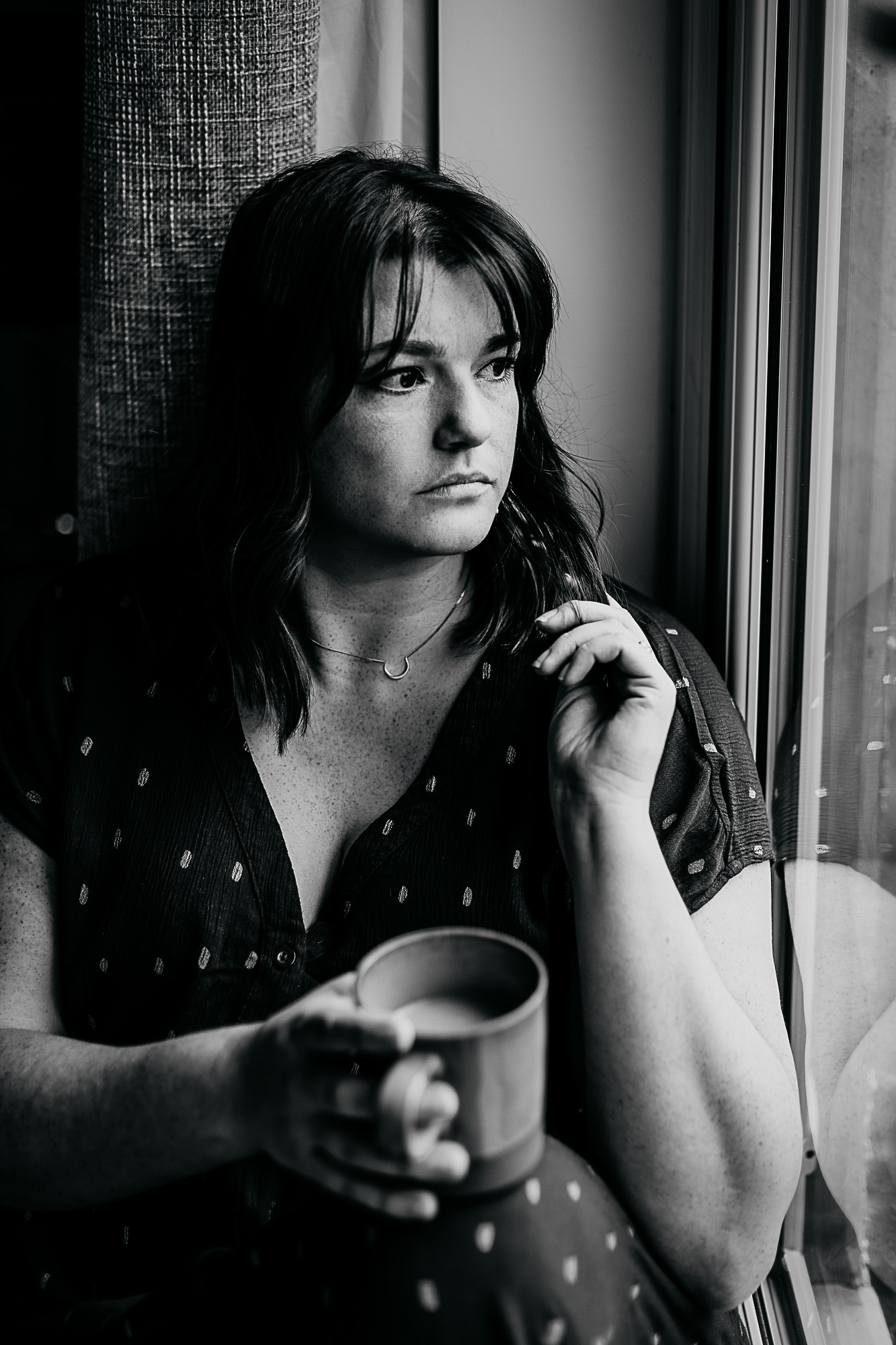 black-and-white-image-of-woman-sitting-looking-out-of-the-window