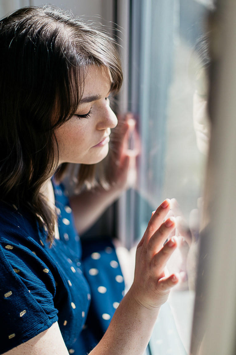 woman-with-hands-against-window-eyes-closed