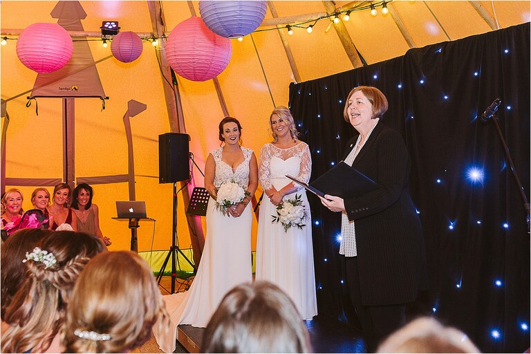 brides-standing-side-by-side-during-wedding-ceremony