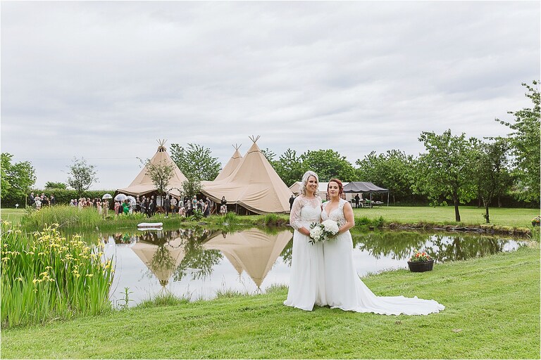 brides-standing-side-by-side-in-front-of-tipi