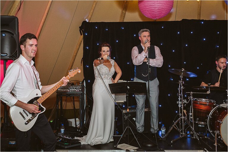 bride-on-stage-with-the-band-pointing-in-to-the-crowd
