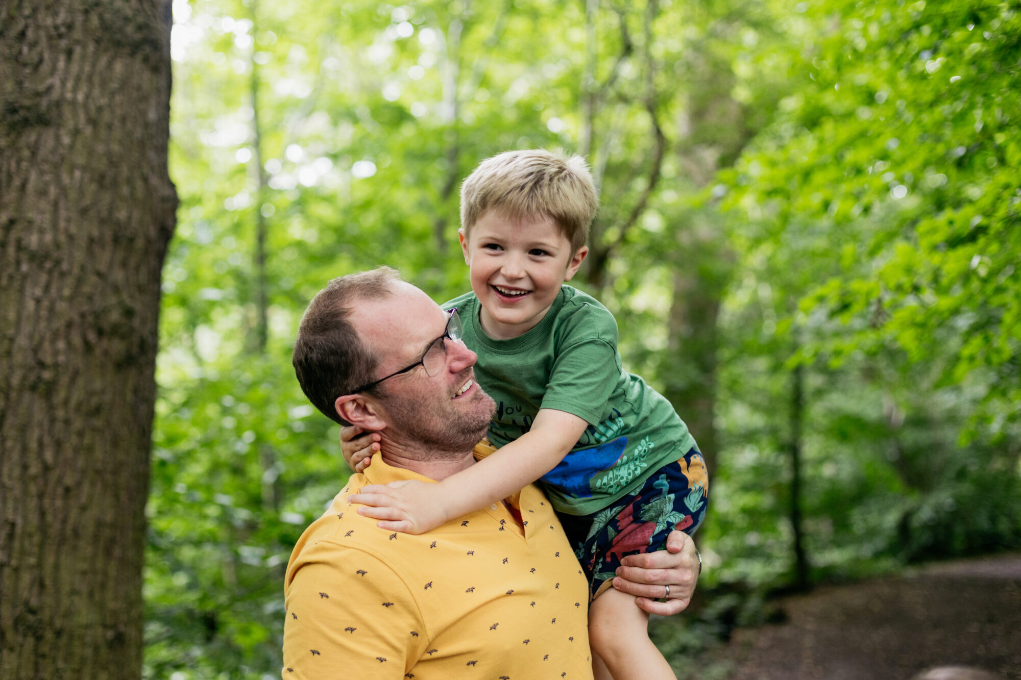 dad-lifting-son-with-one-arm-as-boy-looks-at-camera-at-crossbasket-castle