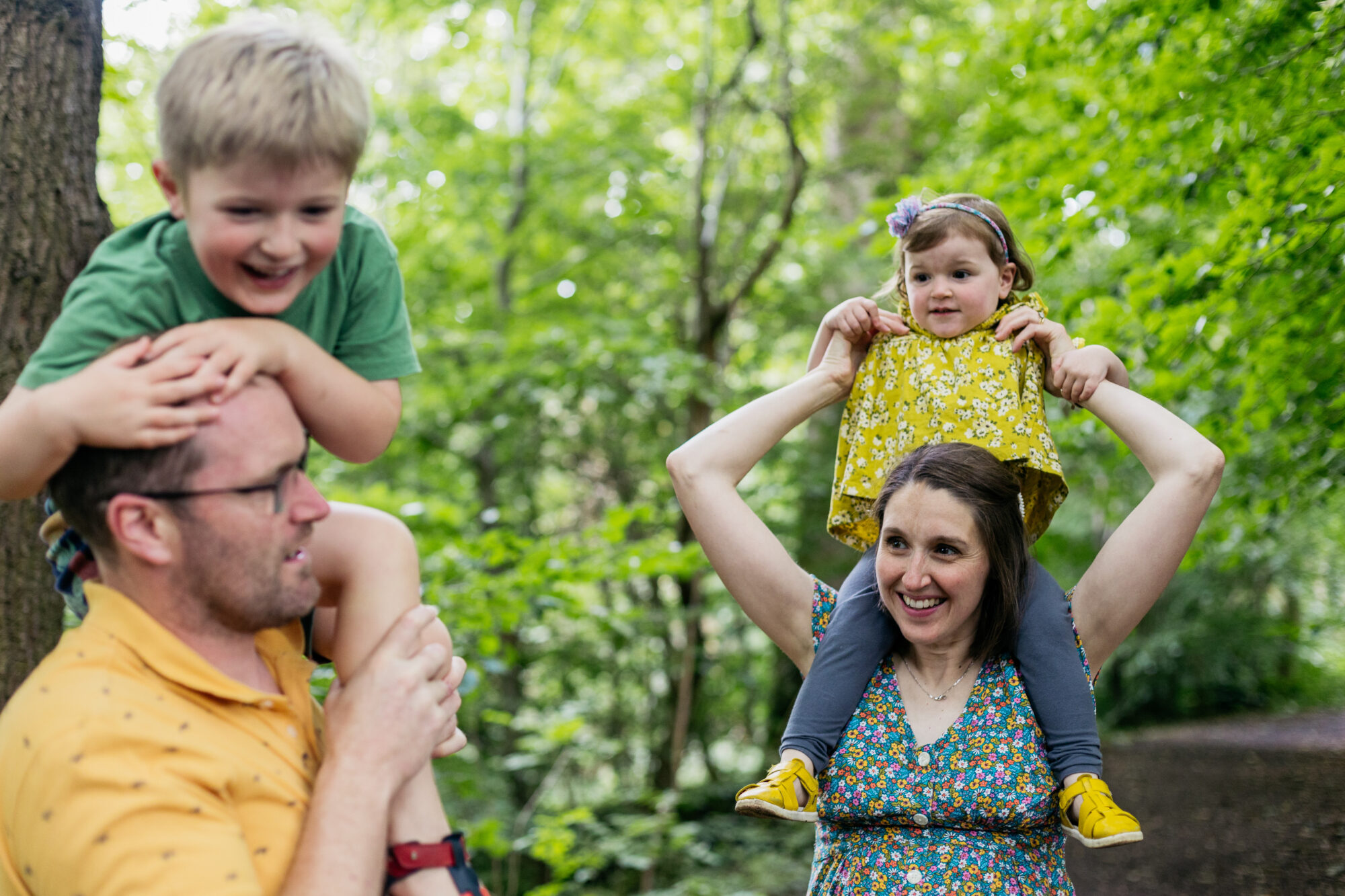 parents-have-lifted-their-children-on-their-shoulders-as-they-walk-through-woods