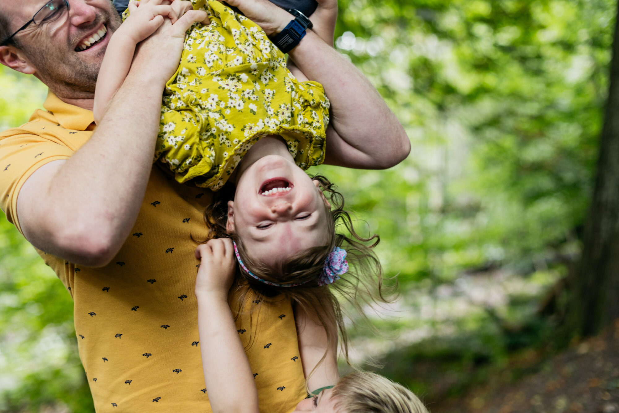 dad-is-holding-daughter-upside-down-to-brother-is-reaching-up-to-tickle-her