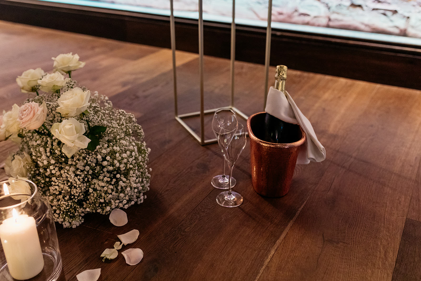 unopened-champagne-bottle-sitting-in-ice-bucket-with-empty-glasses-in-preparation-for-celebrating-proposal