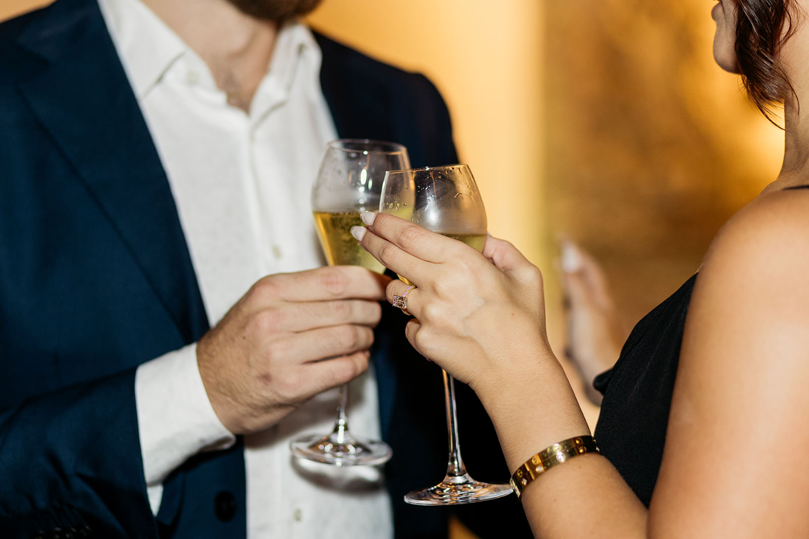 close-up of-couples-hands-as-they-clink-champagne-glasses-just-after-becoming-engaged