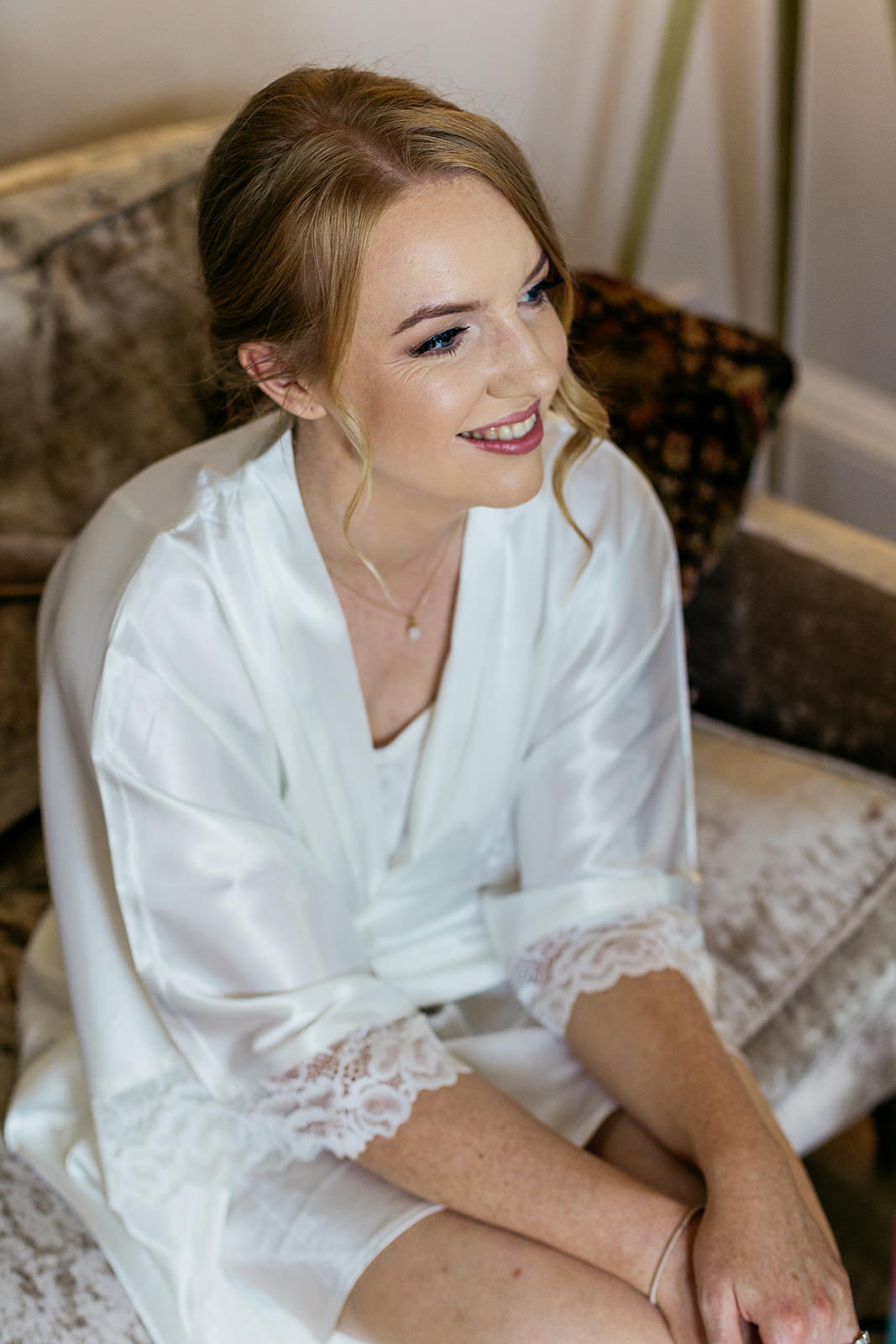 the bride is sitting on the sofa smiling.
