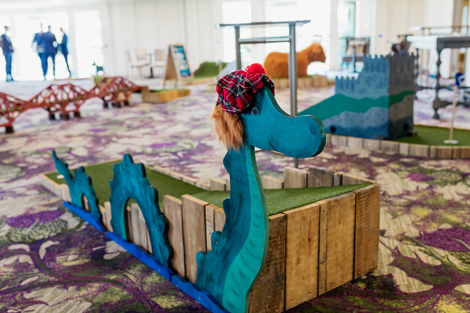 this crazy golf hole has a wooden cut out of the loch ness monster. The monster is wearing a "see you jimmy" hat on its head.