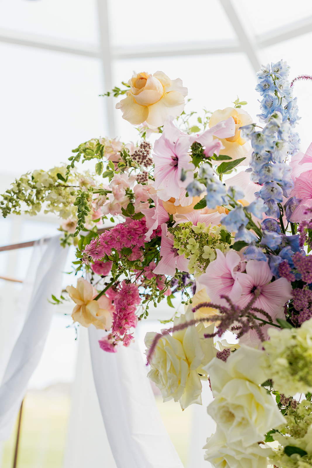 pastel coloured floral arrangement, is tied to the top right corner of a copper frame. there is some netting draped behind it.