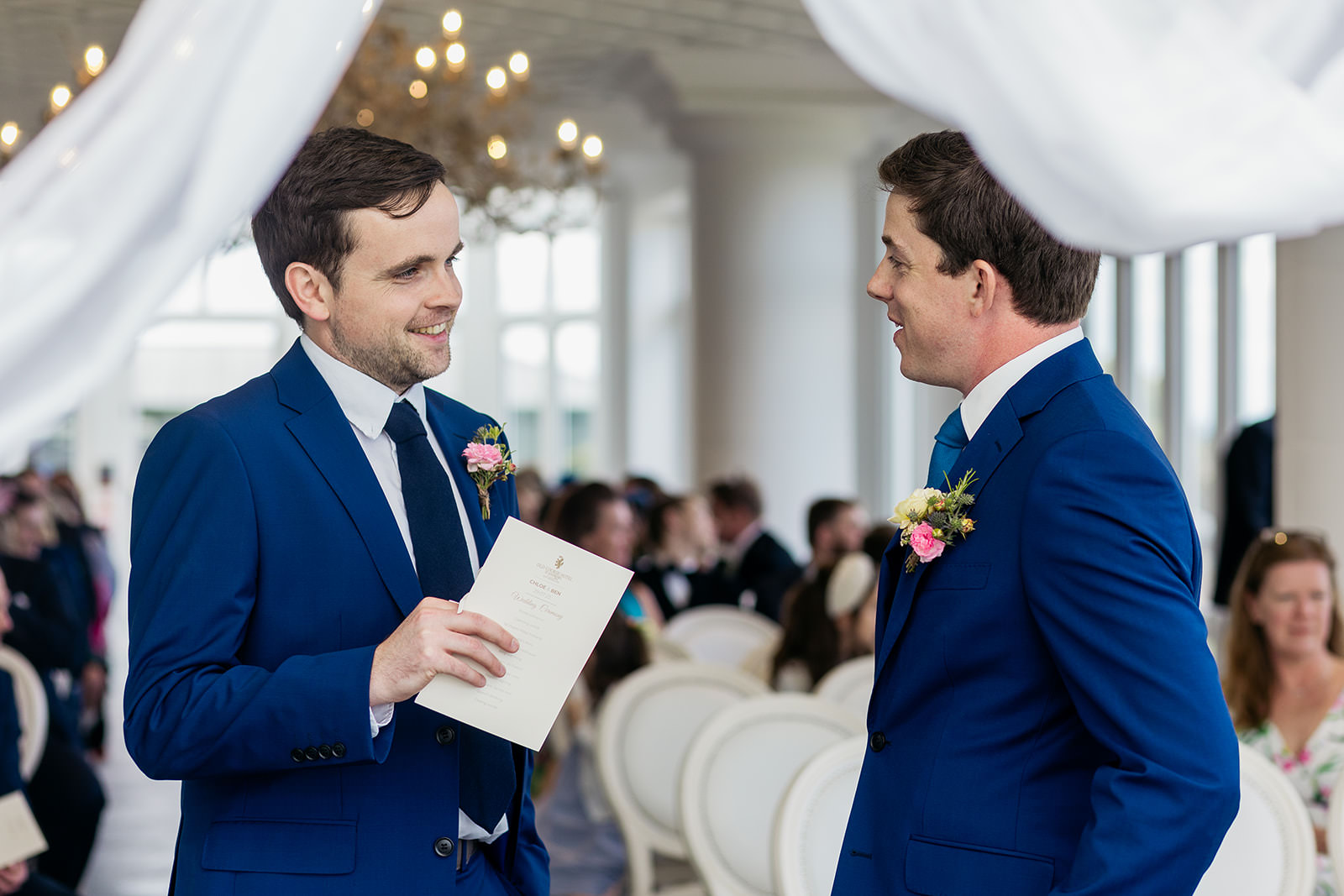 the groom and best man are talking at the top of the wedding aisle as they wait for the ceremony to start.