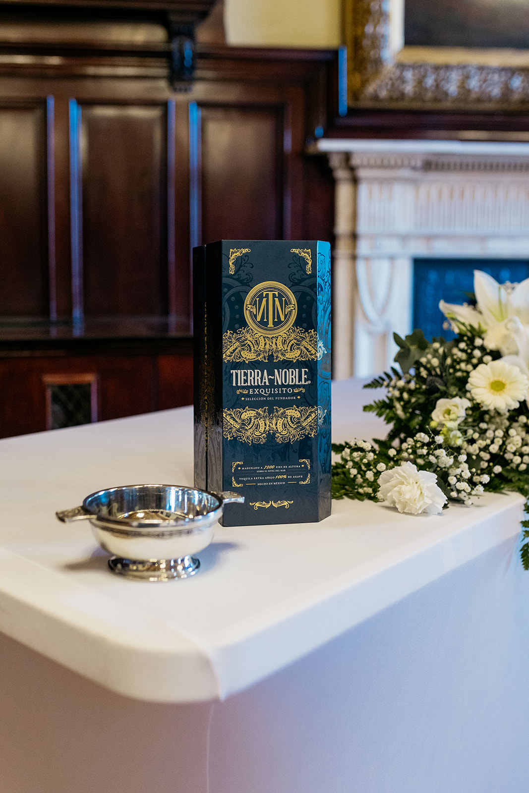 a green box of tierra-noble is sitting on a table. there is a silver quaich in front of the box