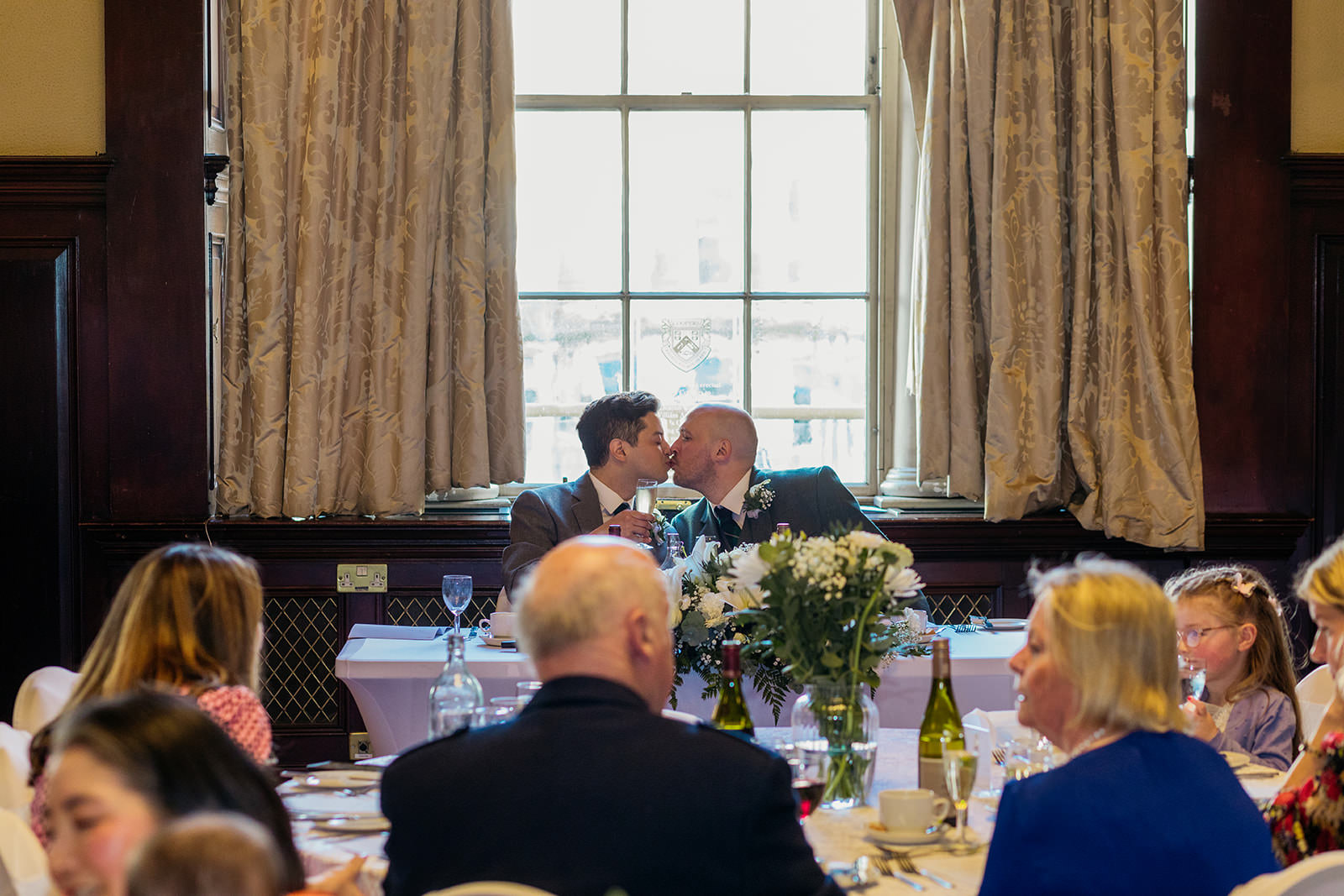 a marred couple share a kiss at their sweetheart table at their wedding reception at the Trades Hall.