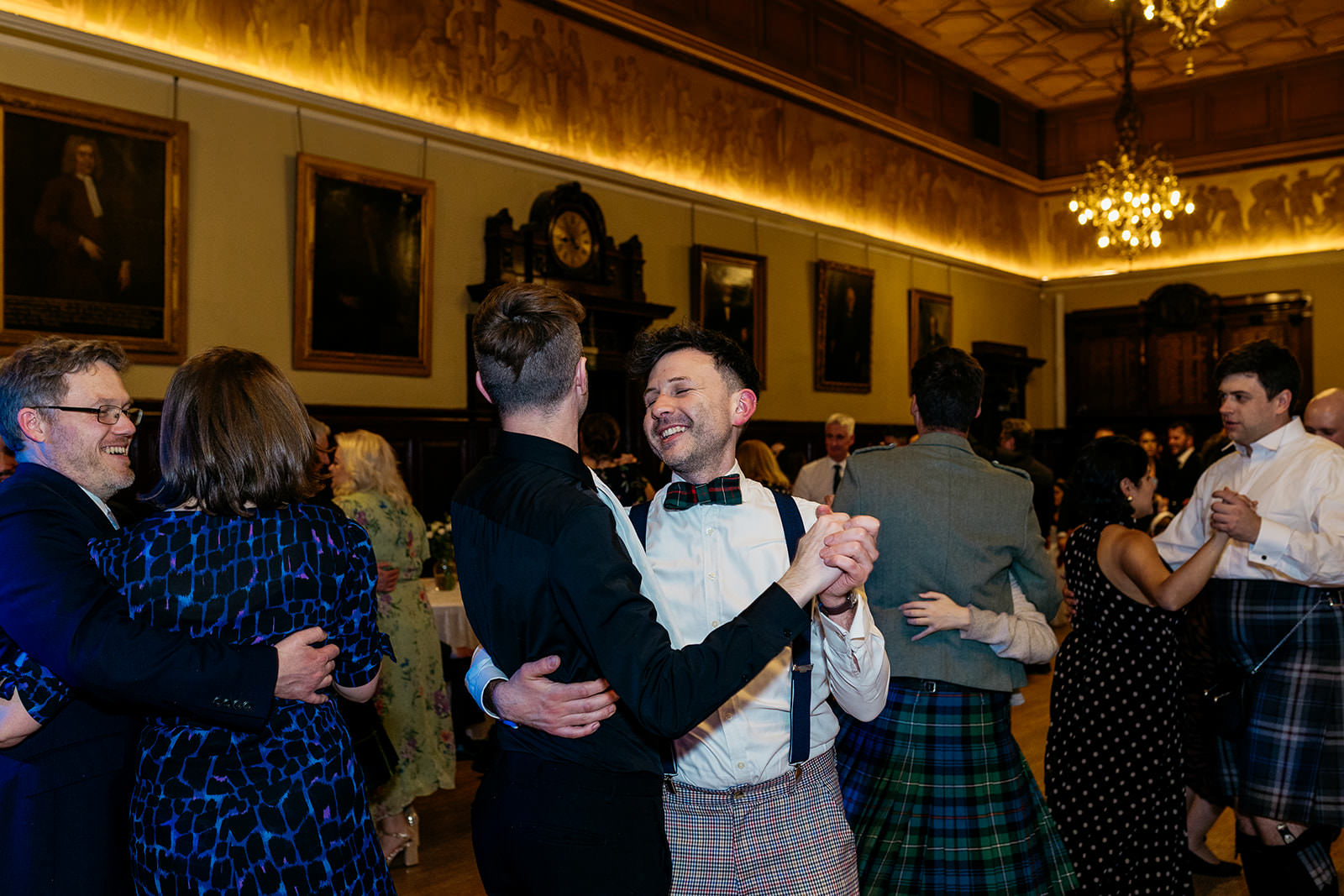 couples are holding each other in a ballroom pose as they dance to some ceilidh music. they are smiling at each other.