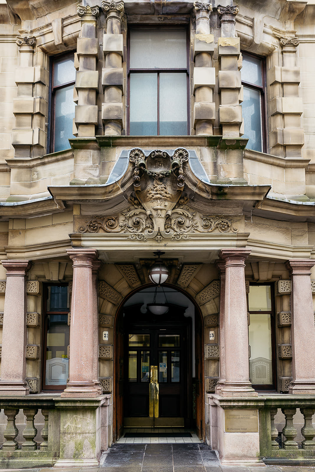 the outside of 23 montrose street registry office. there is an intricately craved design in the stone above the door and the facade is supported by pink stone columns.