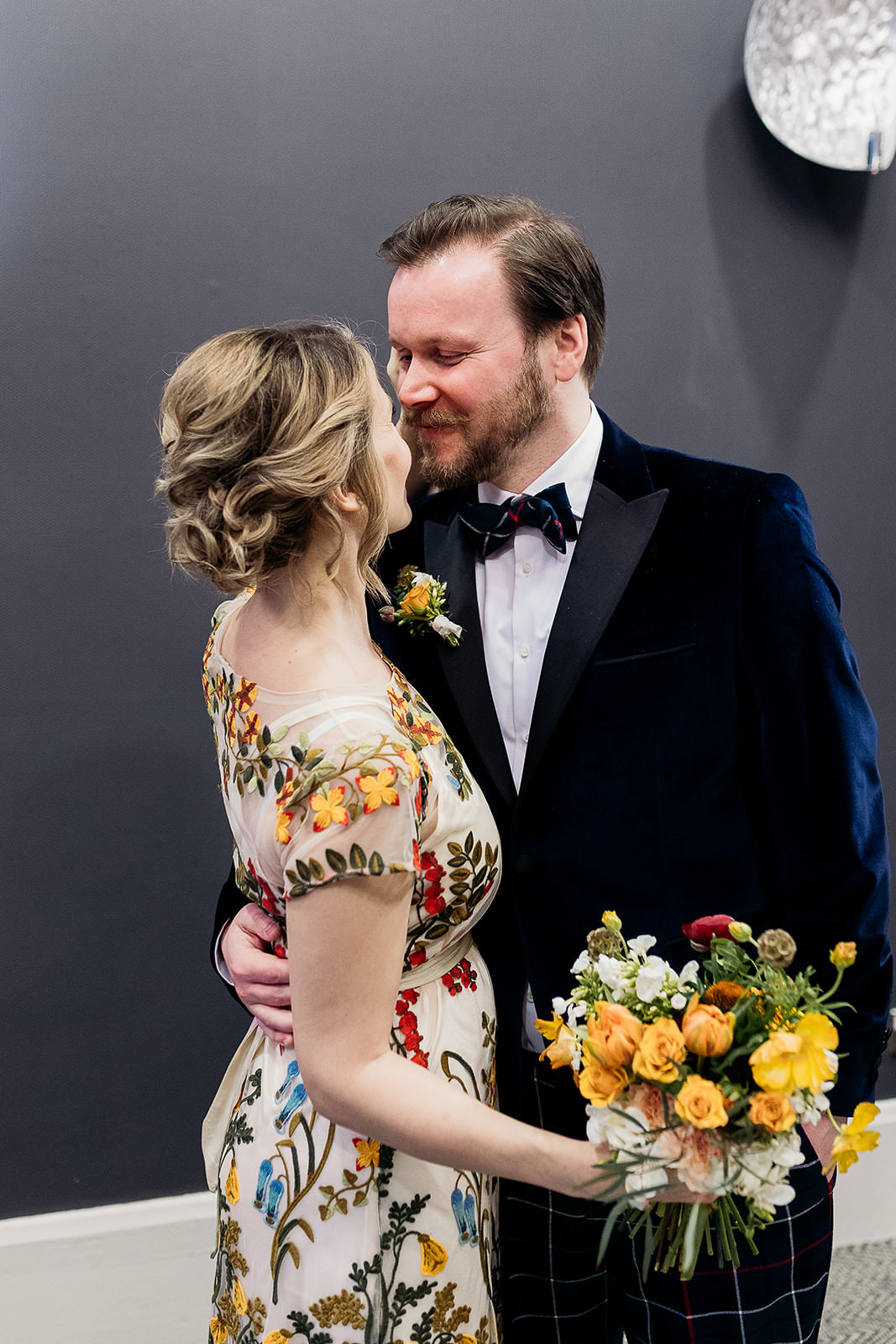 a man is facing a woman and he has his hand around her waist. they are looking at each other and smiling. their faces are close together.