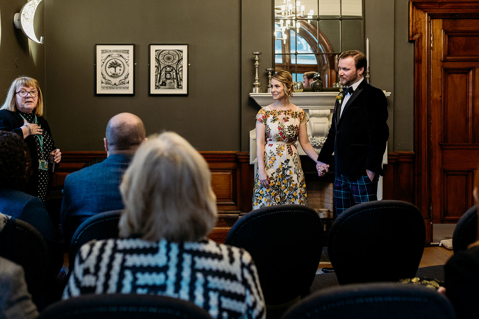a bride and groom are holding hands as they listen to their celebrant talk during their ceremony.