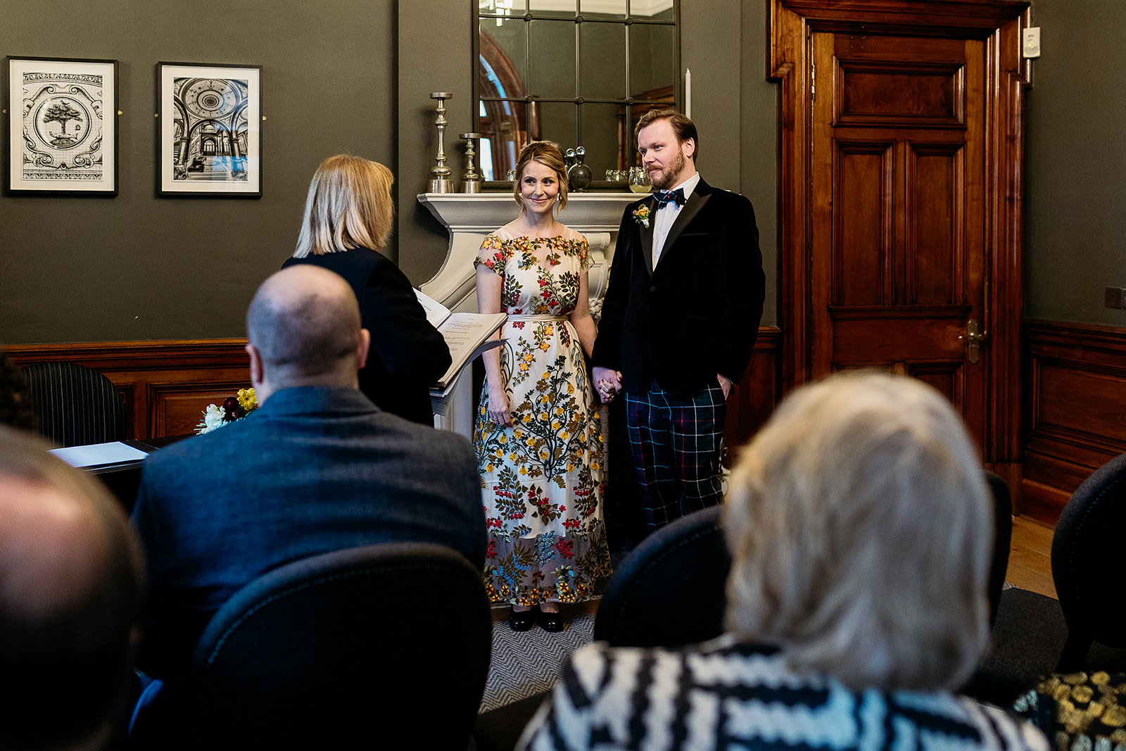 a bride and groom are standing side by side, holding hands. they are facing the celebrant and listening to them.