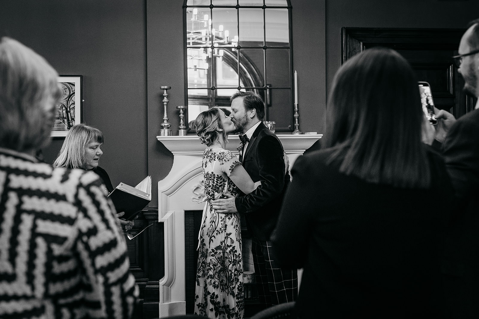a bride and groom as kissing and are surrounded by their guests.